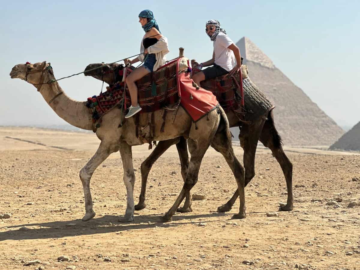 a couple of people riding on the back of a camel